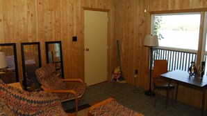 Ein Holzinterieur mit einer Couch, Stühlen, einem Tisch und einem Fenster.