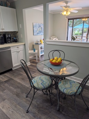 A dining area with a glass table, metal chairs, and a bowl of lemons.