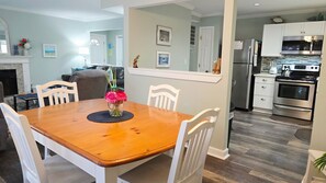 A dining area with a wooden table, white chairs, and a vase of flowers. - Fall is beautiful,beach locker & chairs/ 8 min walk to Shipyard Beach (Hilton Head Island)