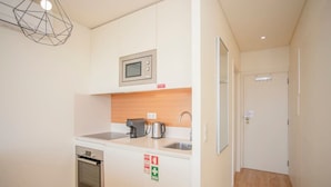 A compact kitchenette with a microwave, coffee maker, and oven.