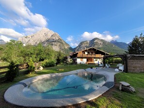 A mountain lodge with a swimming pool, surrounded by lush greenery and mountains. - Housemuhlbach Wellness Acqua Spa Resort (Sappada)
