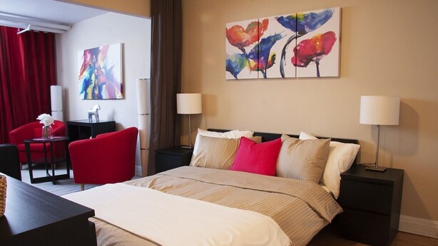 Een hotelkamer met een bed, twee nachtkastjes, een bureau, een stoel en twee schilderijen aan de muur.