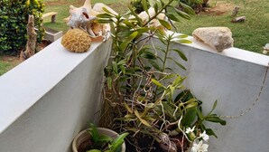 Un balcon agrémenté de plantes en pot, une petite vue sur le jardin et une sculpture en pierre.