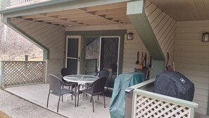 Een overdekt terras met een tafel, stoelen, een barbecue en een schuifpui.