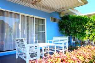 Un patio con mobiliario blanco y una pared azul.