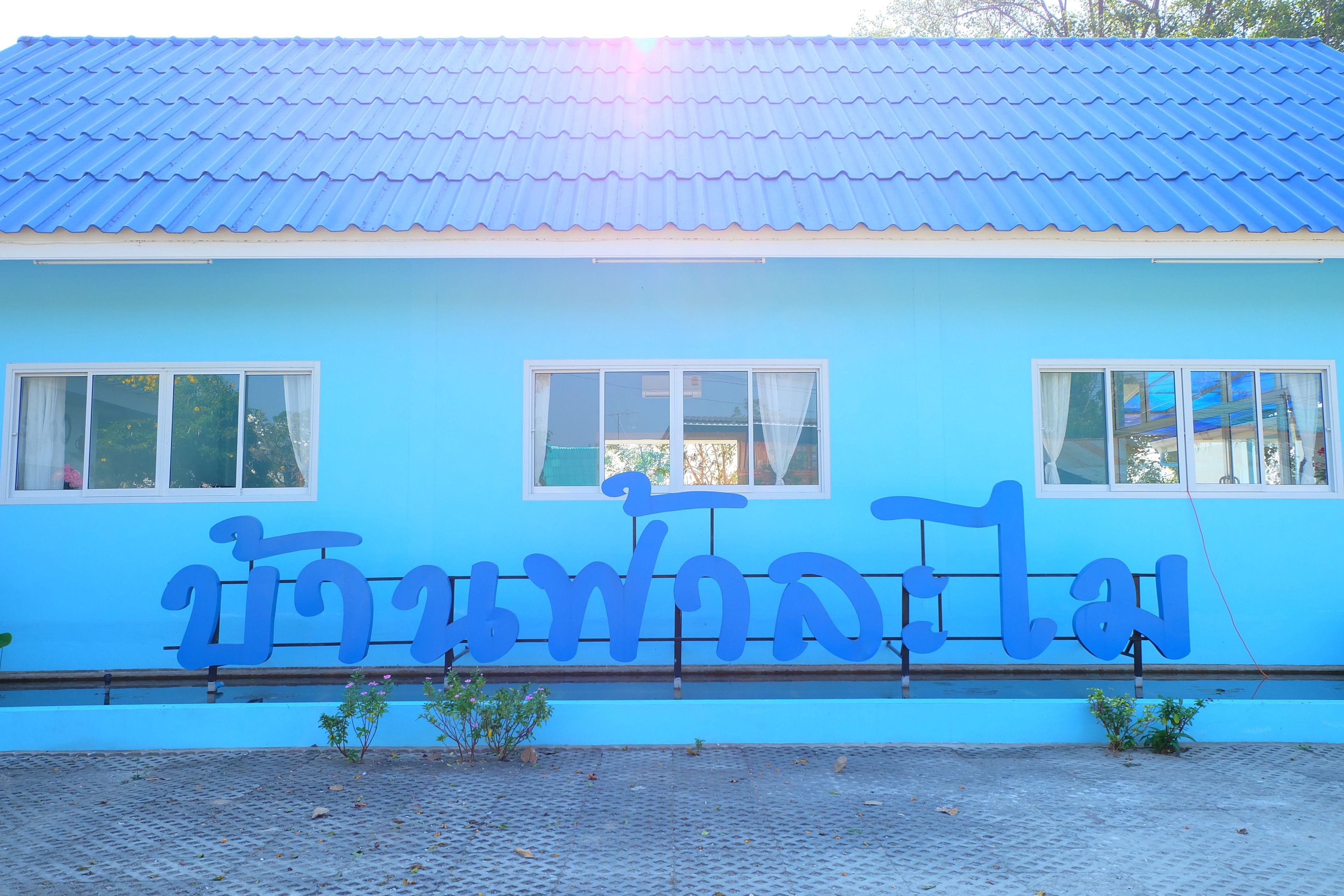 Um edifício com fachada azul e uma placa com escrita tailandesa.