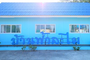 A building with a blue exterior and a sign with Thai script. - Baan Fa La Mai Resort (Tak)