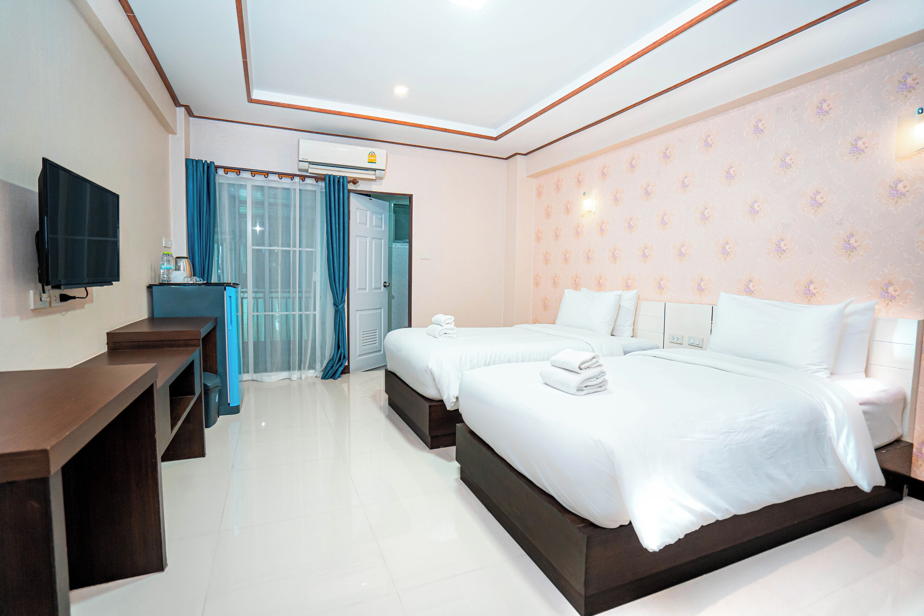 A hotel room with two beds, a desk, a TV, and a bathroom visible through a door.