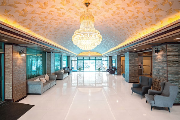 Un hall d’entrée spacieux, agrémenté d’un grand lustre, de coins salon et offrant une vue sur l’extérieur.