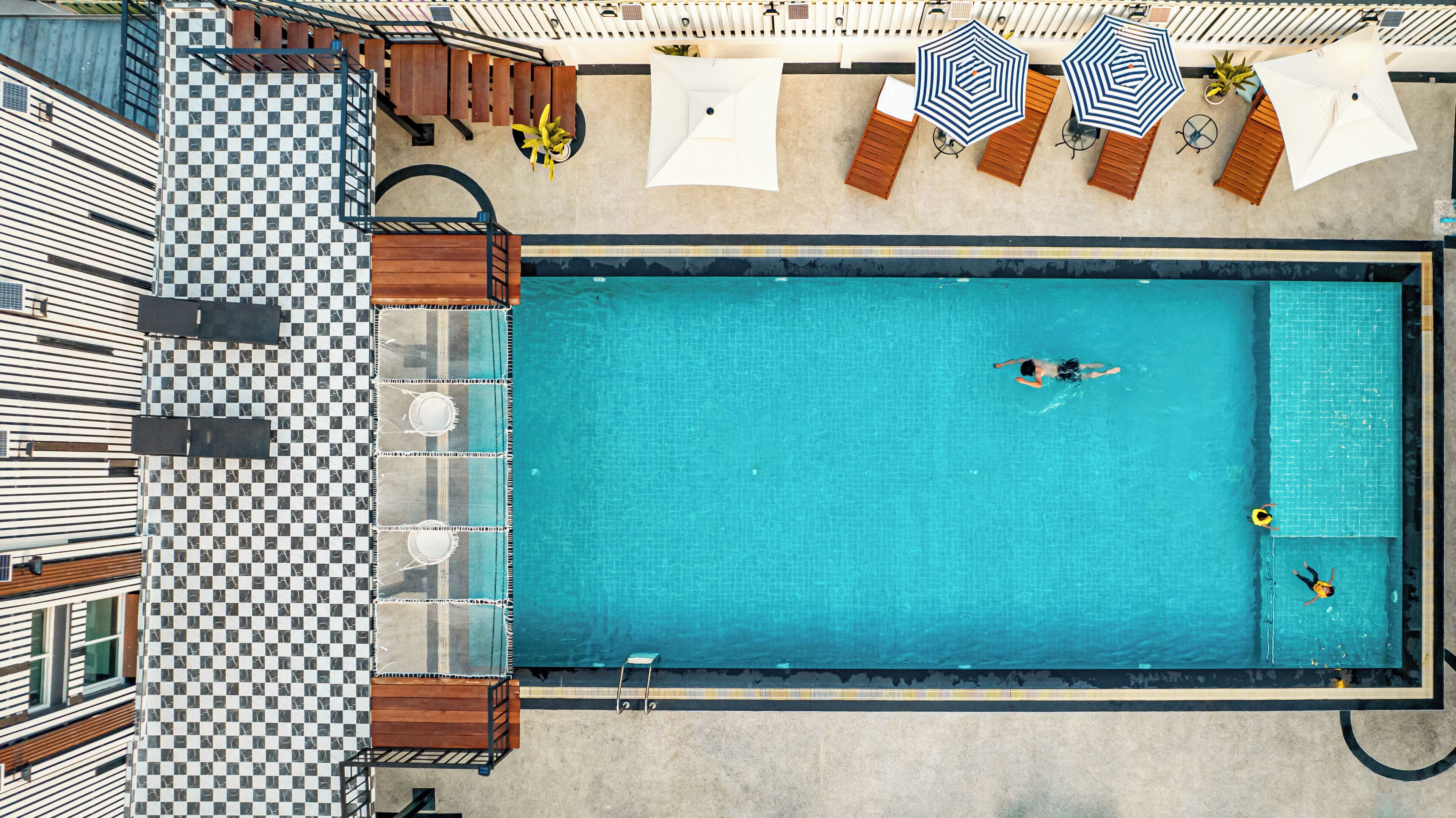 An aerial view of a swimming pool with lounge chairs and umbrellas.