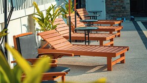 Terrassenstühle und Tische entlang der Außenwand eines Gebäudes.