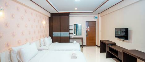 A hotel room with two beds, a TV, a desk, and a wardrobe.