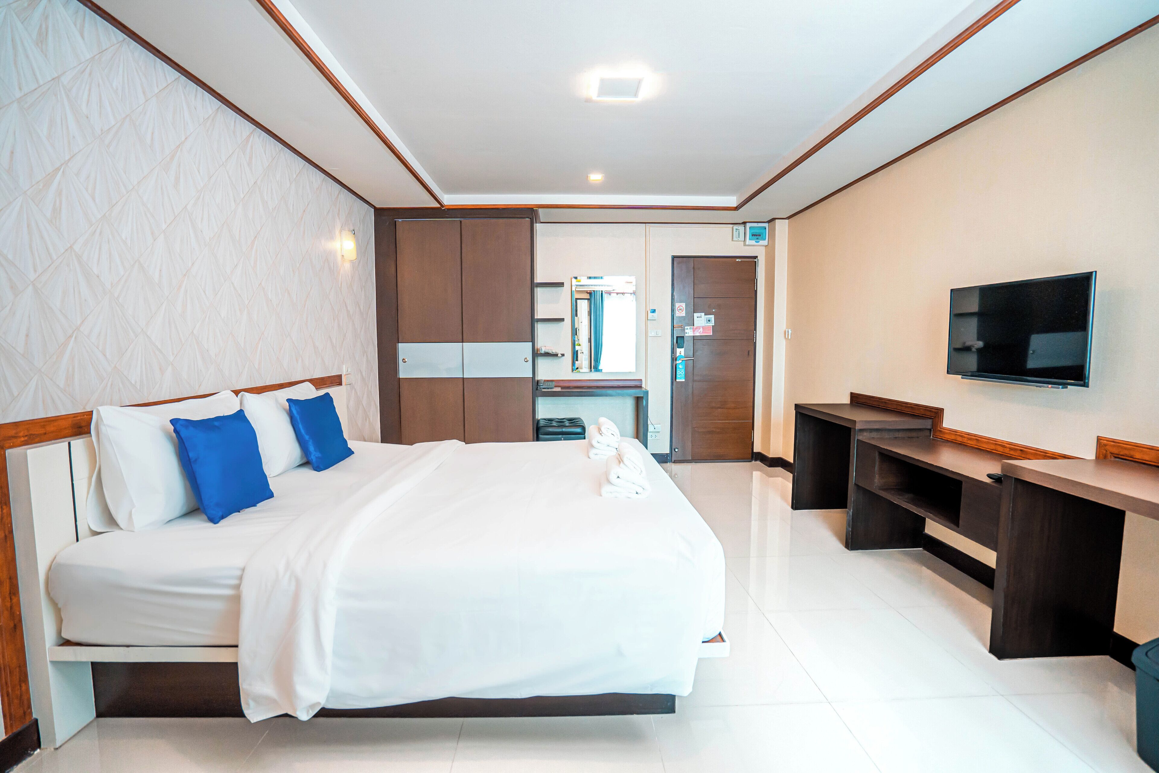 Une chambre d’hôtel avec un grand lit, un bureau, un téléviseur à écran plat et une salle de bain visible à travers une porte.