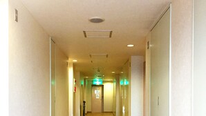 A hotel hallway with a tiled floor, doors on both sides, and a sign at the end. - Koga Ark Hotel (Koga)
