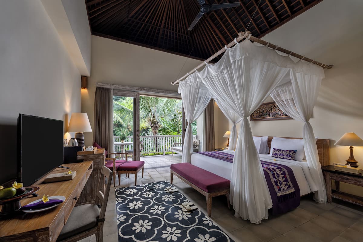 A bedroom with a four-poster bed, a bench, a TV, and a dining area with a table and chairs.