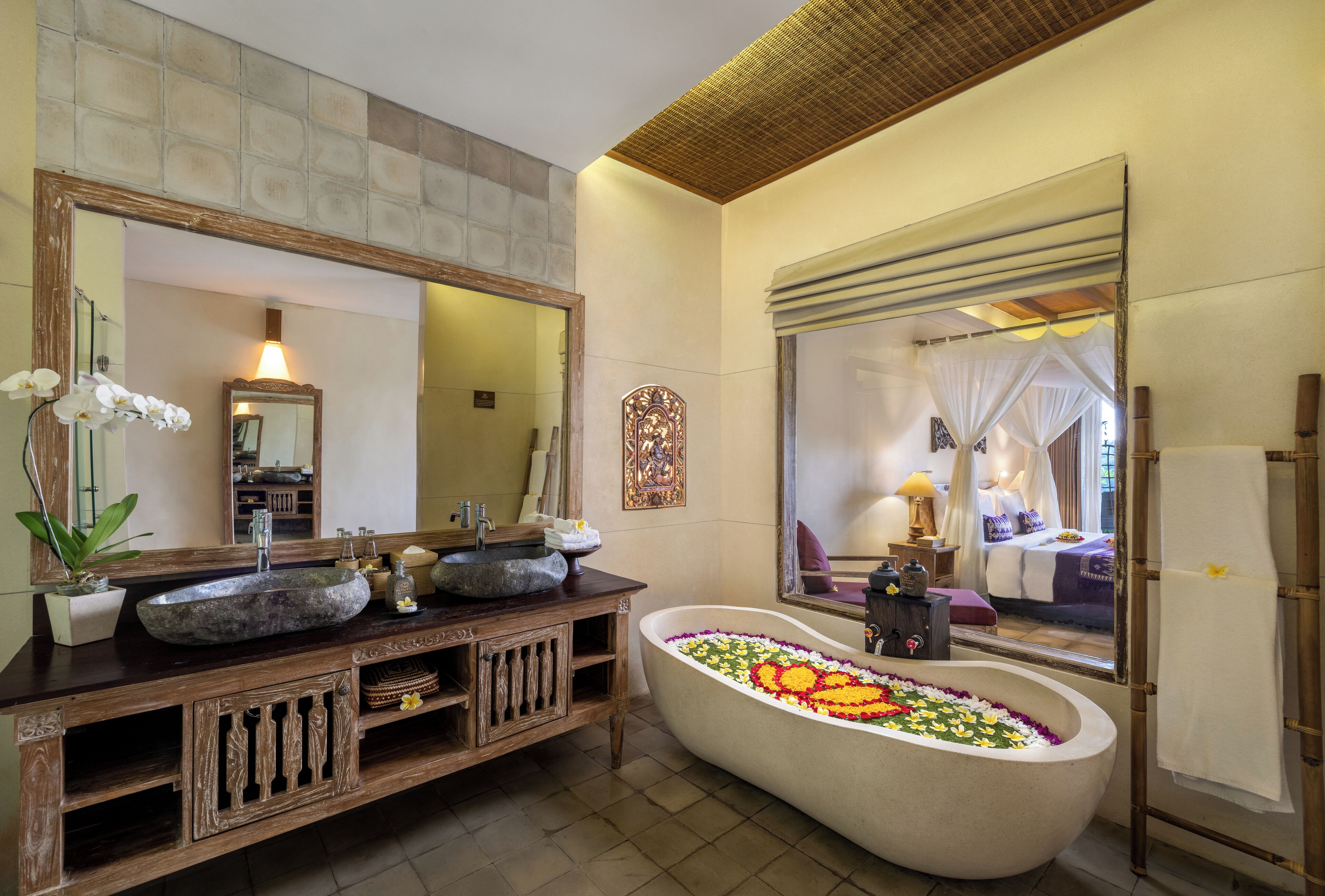 A bathroom with a freestanding bathtub, a large mirror, and a wooden vanity.