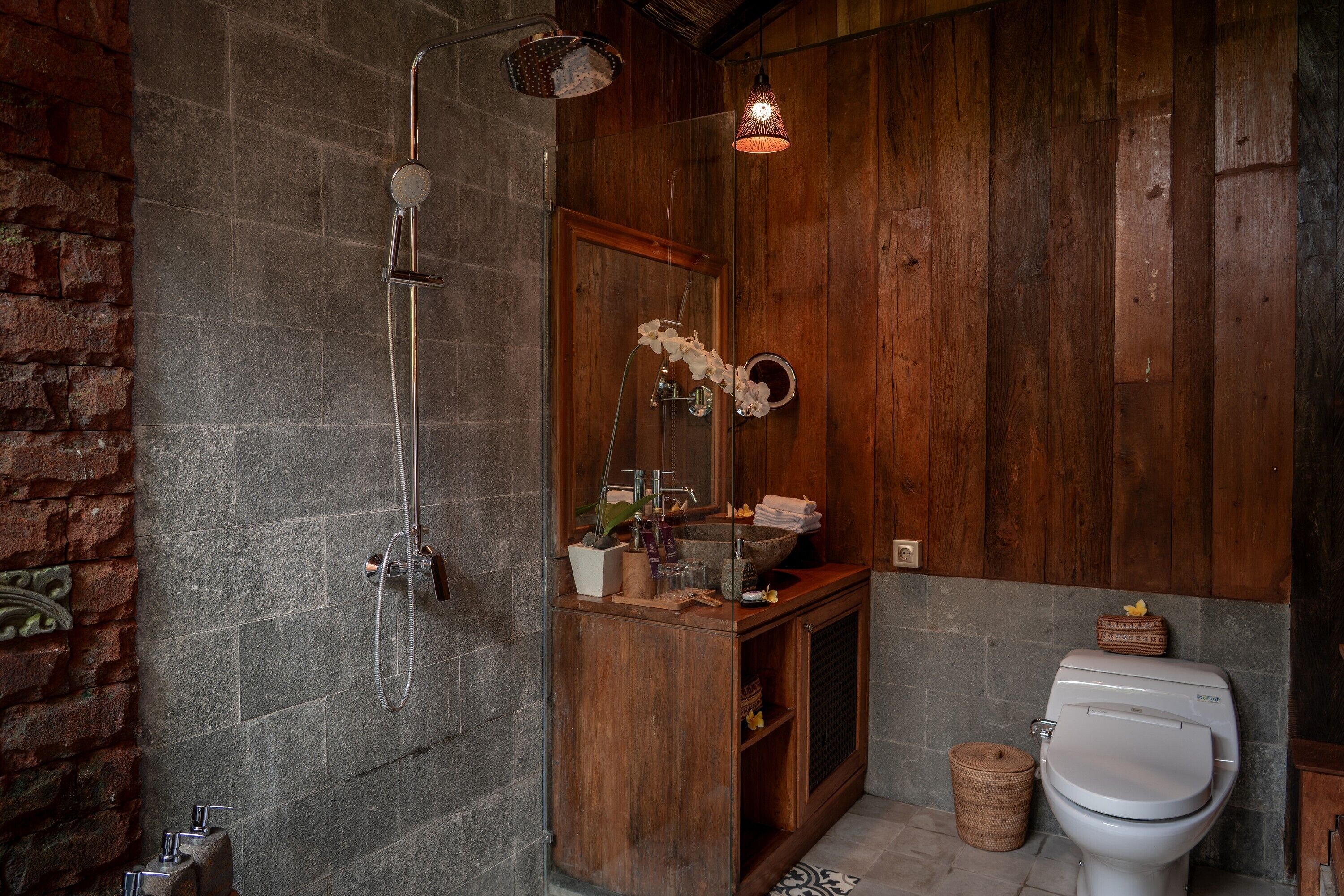A bathroom with a shower, a sink, a toilet, and a mirror.