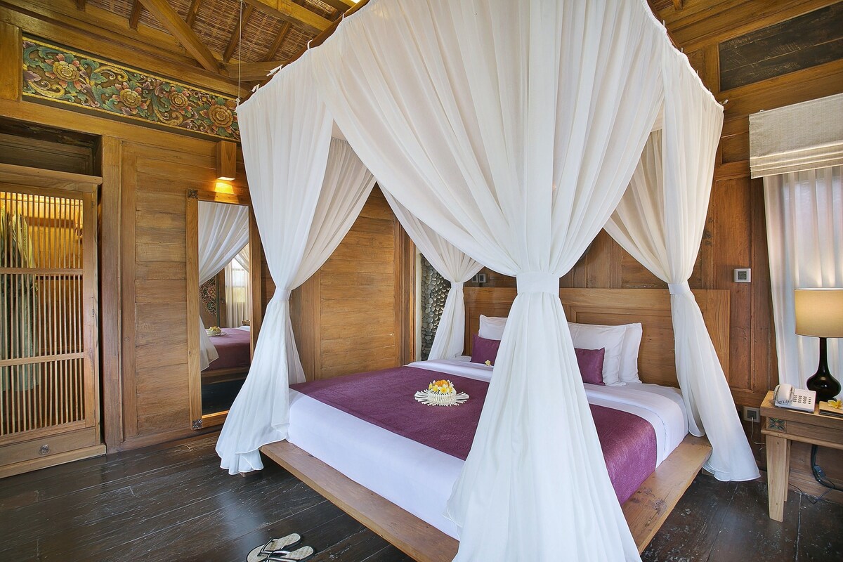 Una habitación con cama con dosel, paredes de madera, un espejo y una mesita de noche con lámpara.