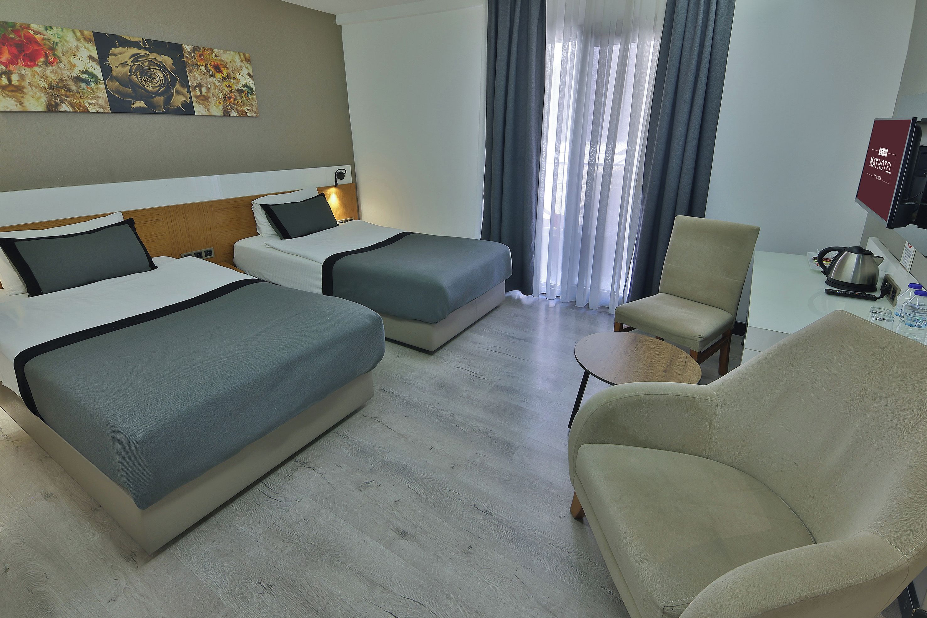 Een hotelkamer met twee bedden, een stoel, een bureau en een televisie.