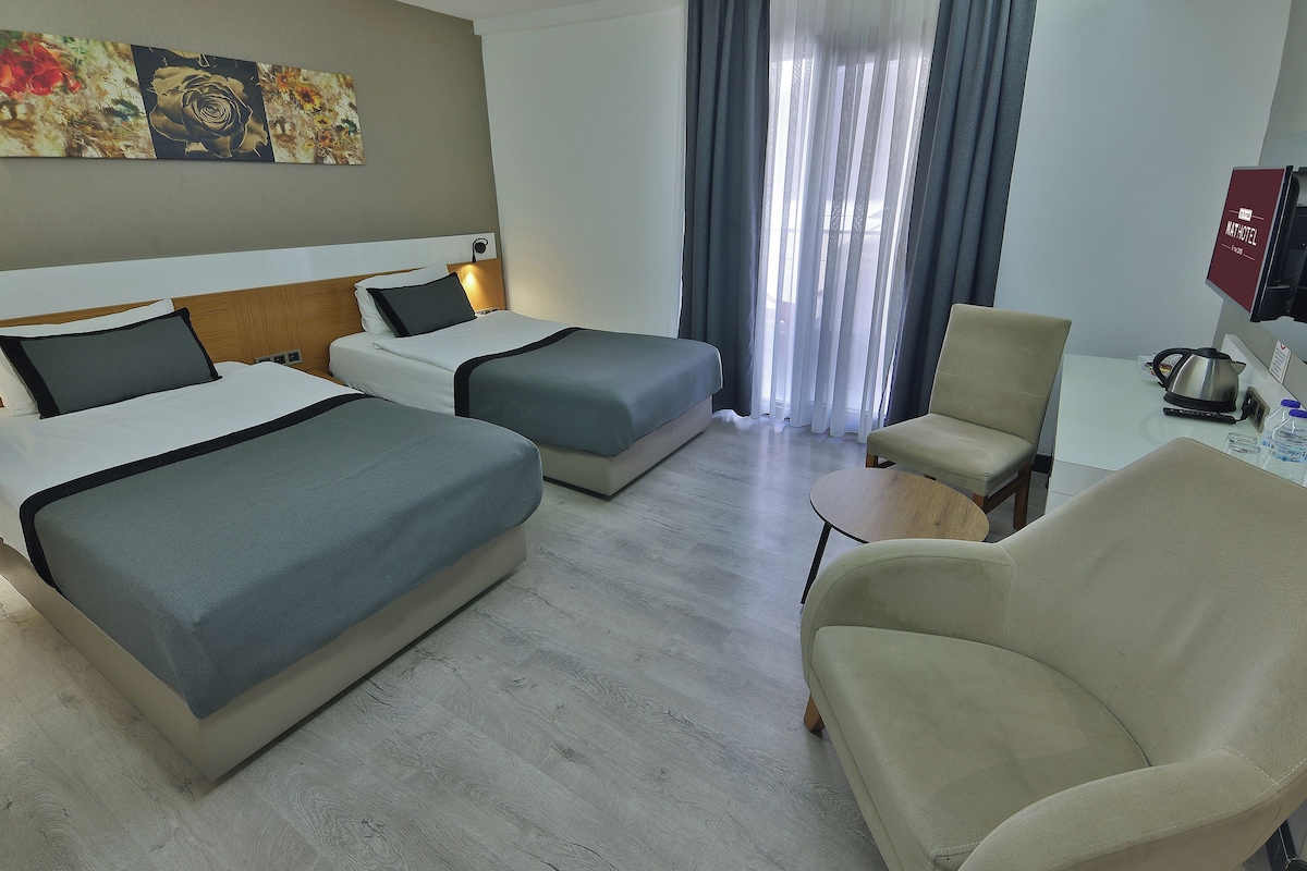 Una habitación de hotel con dos camas, una silla, un escritorio y un televisor.
