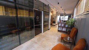 A modern interior with glass walls, a reception desk, and seating areas. - BUCA MAT HOTEL BY TAHTALI (Izmir)