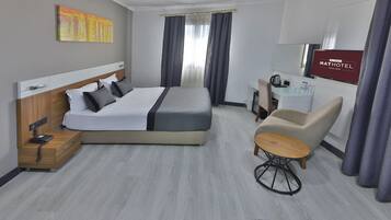 A modern hotel room with a large bed, a desk, a chair, and a TV.