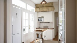 A modern kitchen with white cabinetry, a built-in microwave, and a wooden island with a sink.