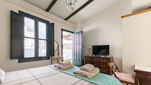 A bedroom with a bed, a dresser, a chair, a television, and a window.