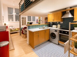 A modern kitchen with wooden cabinets, a built-in washing machine, and a patterned floor.
