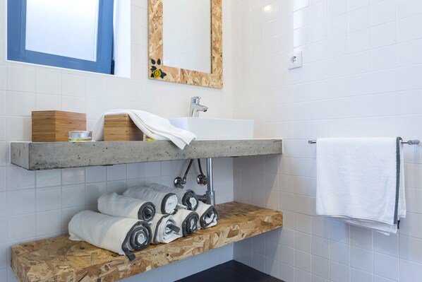A bathroom with a wooden vanity, a white sink, and a towel rack. - Quinta das Rosas Villas - Yellow Rose (Ribeira Grande)
