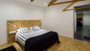 Een moderne slaapkamer met een houten hoofdbord, een bed met gestreept beddengoed, een nachtkastje en een bijzettafeltje.