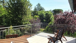 Ein Balkon mit Holztisch und -stühlen, umgeben von einem Metallgeländer.