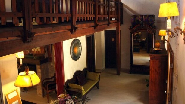 Ein Zimmer mit hohen Decken, einem Holzbalkon, einer Couch und einer Lampe.