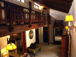 A high-ceilinged room with a wooden balcony, a sofa, and a lamp.