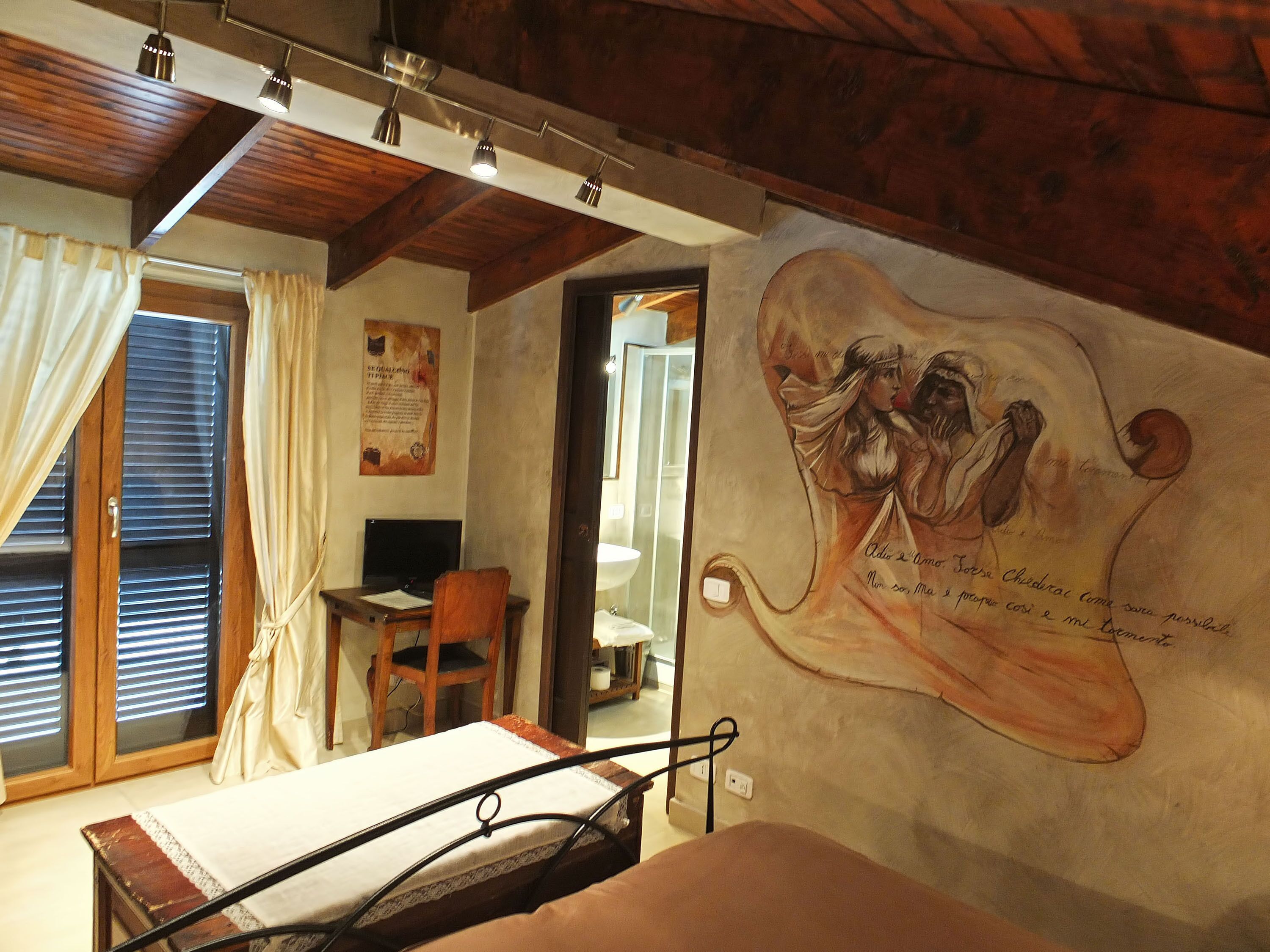 A bedroom with a bed, a desk, a chair, and a mural on the wall.
