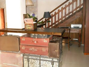 A staircase with a wooden railing, a desk with a lamp, and stacked luggage in the foreground. - Nostra Signora del Lago (Ronciglione)