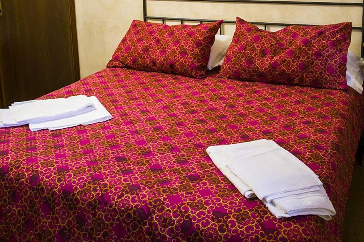A hotel room with a bed, a painting on the wall, and a door.