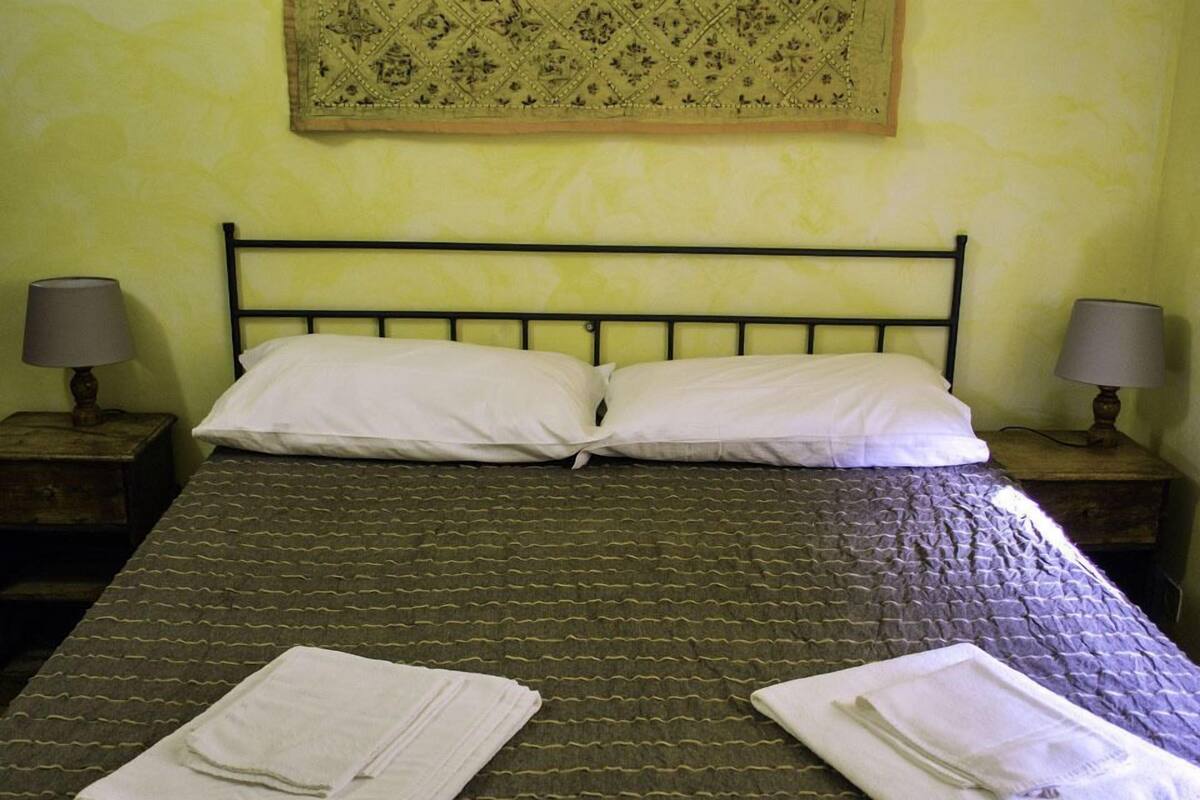 A bed with a metal frame, two pillows, and two folded towels on the bed.