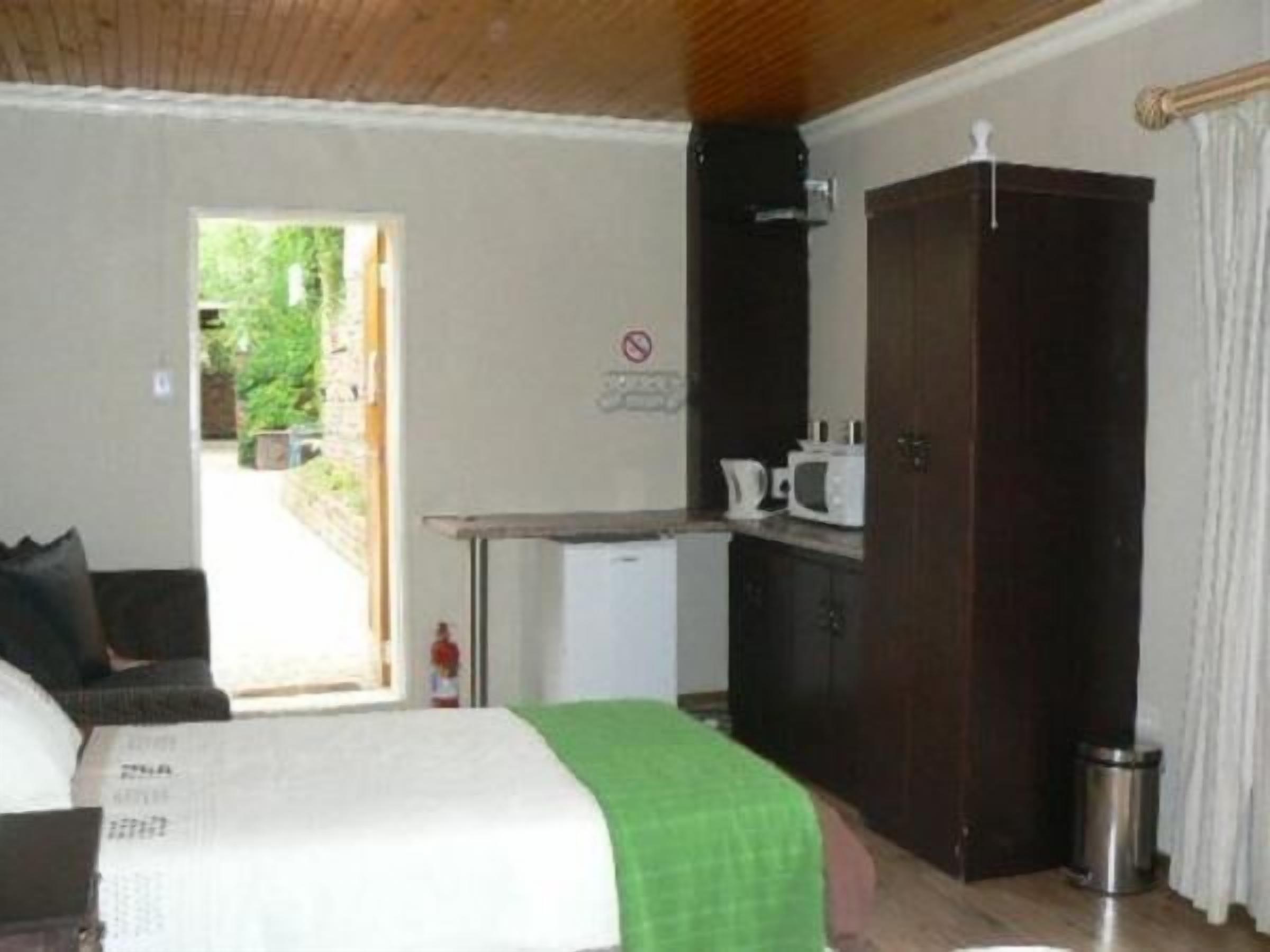 Una habitación con cama, un escritorio con microondas, un armario y una puerta que da al exterior.