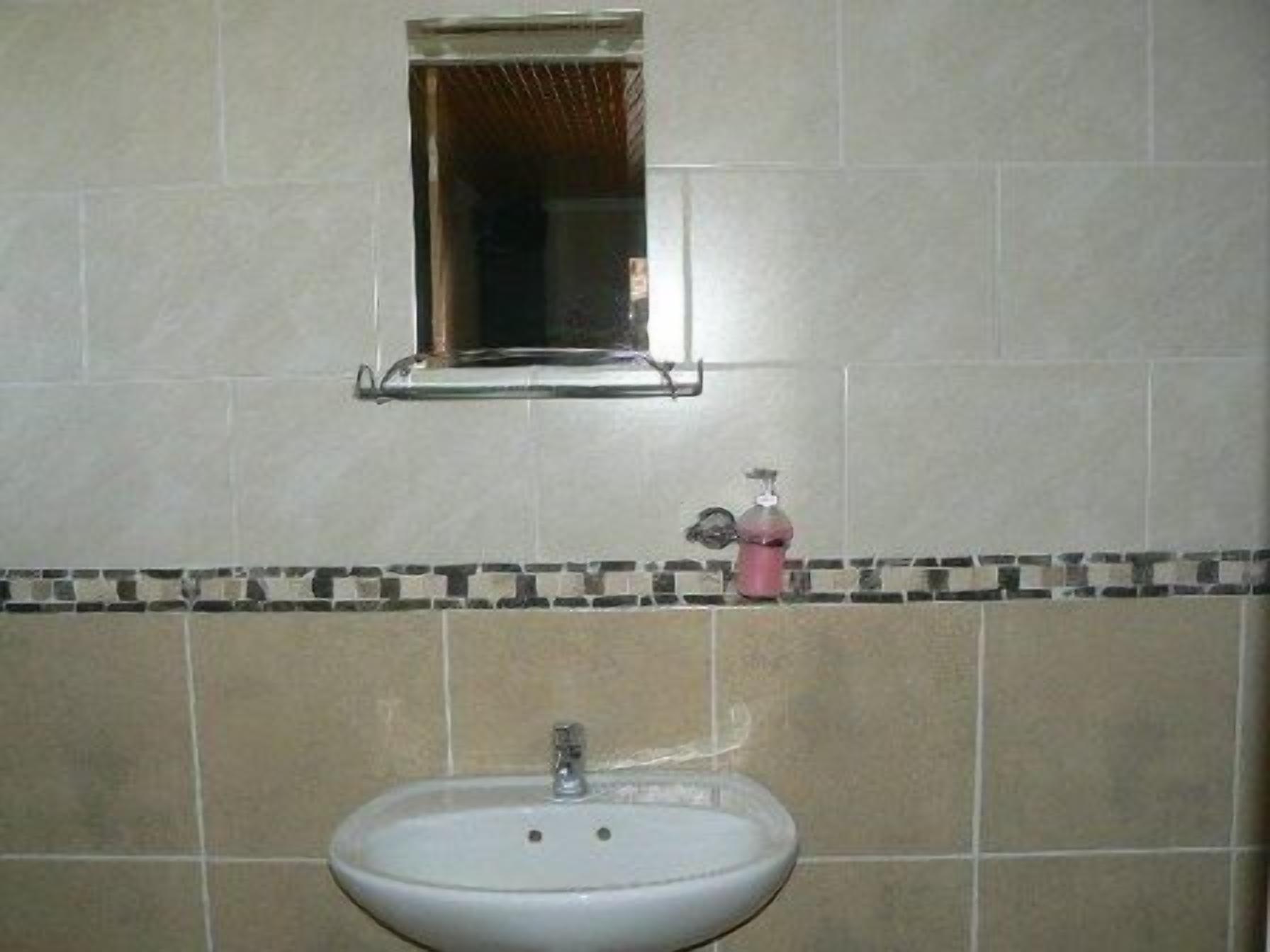 A bathroom with a sink, a mirror, and a soap dispenser.