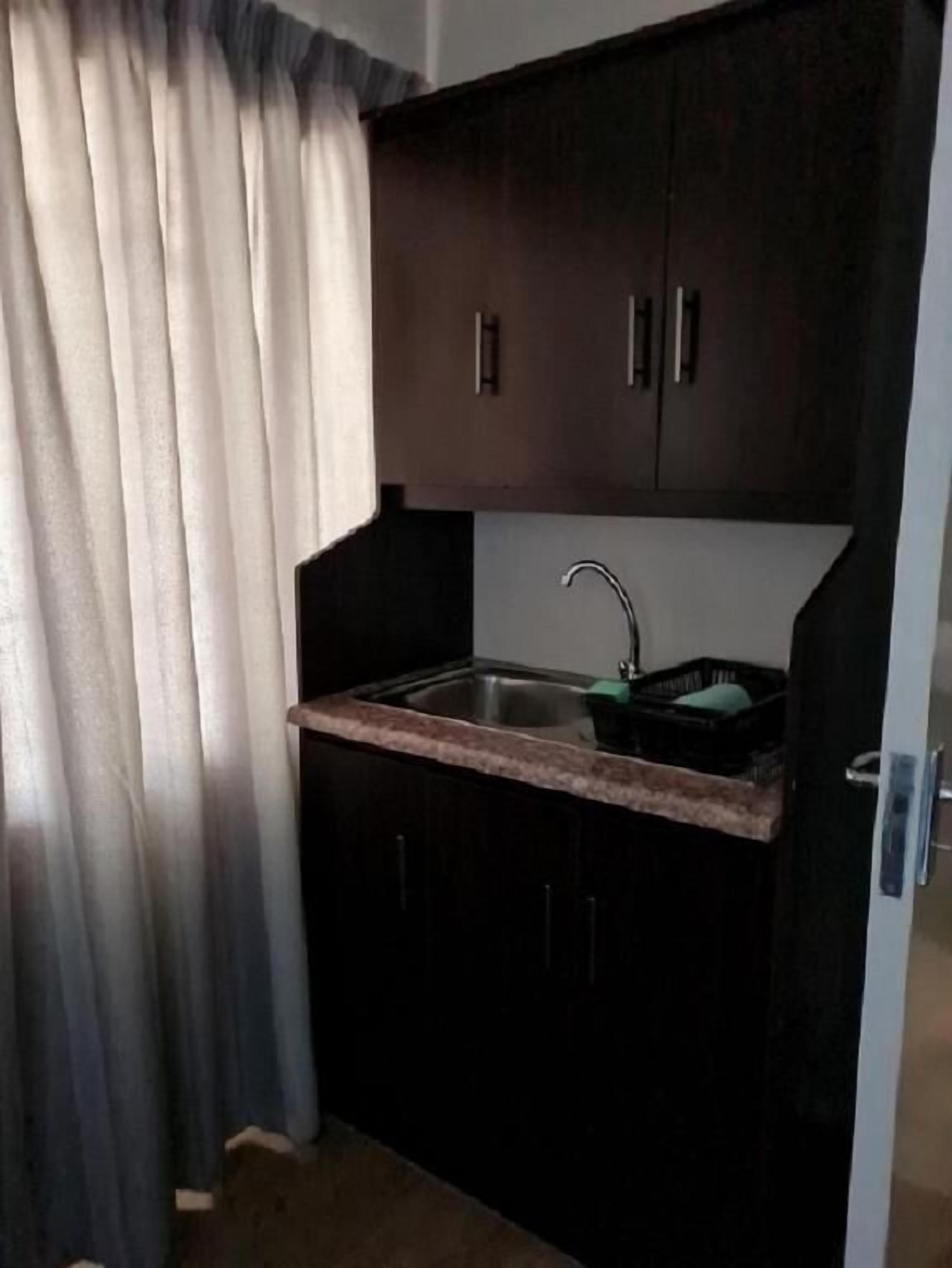 Una cocina compacta con armarios oscuros, un lavamanos de acero inoxidable y una encimera.