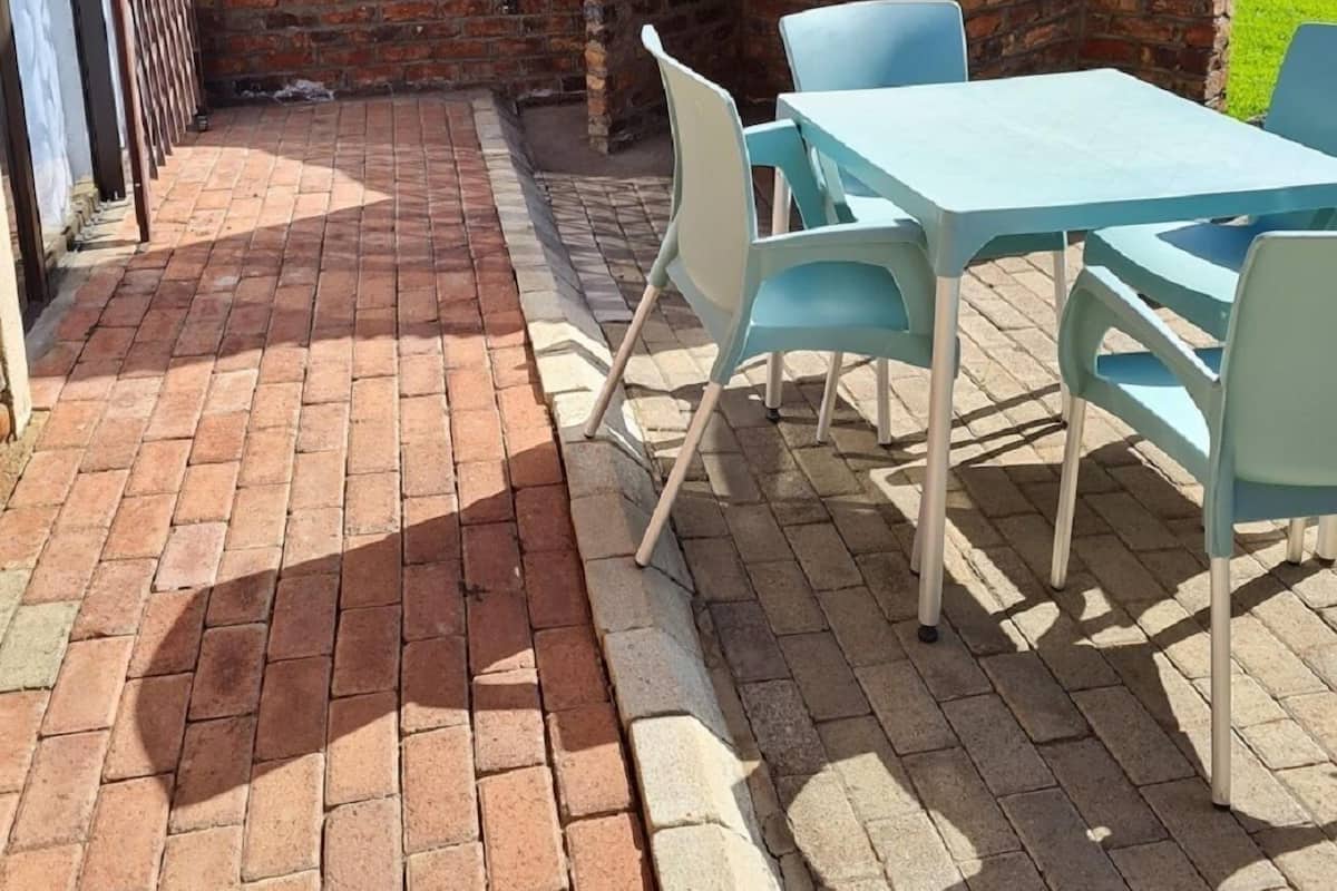 Eine Terrassengaststätte mit Ziegelmauer, einem Backofen aus Ziegeln und einem Tisch mit Stühlen.