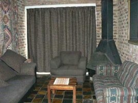 Una sala acogedora con un tapete estampado, un sofá, un sillón y una pequeña mesa de madera.