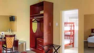 A hotel room with a desk, chair, wardrobe, bunk bed, and a bed.