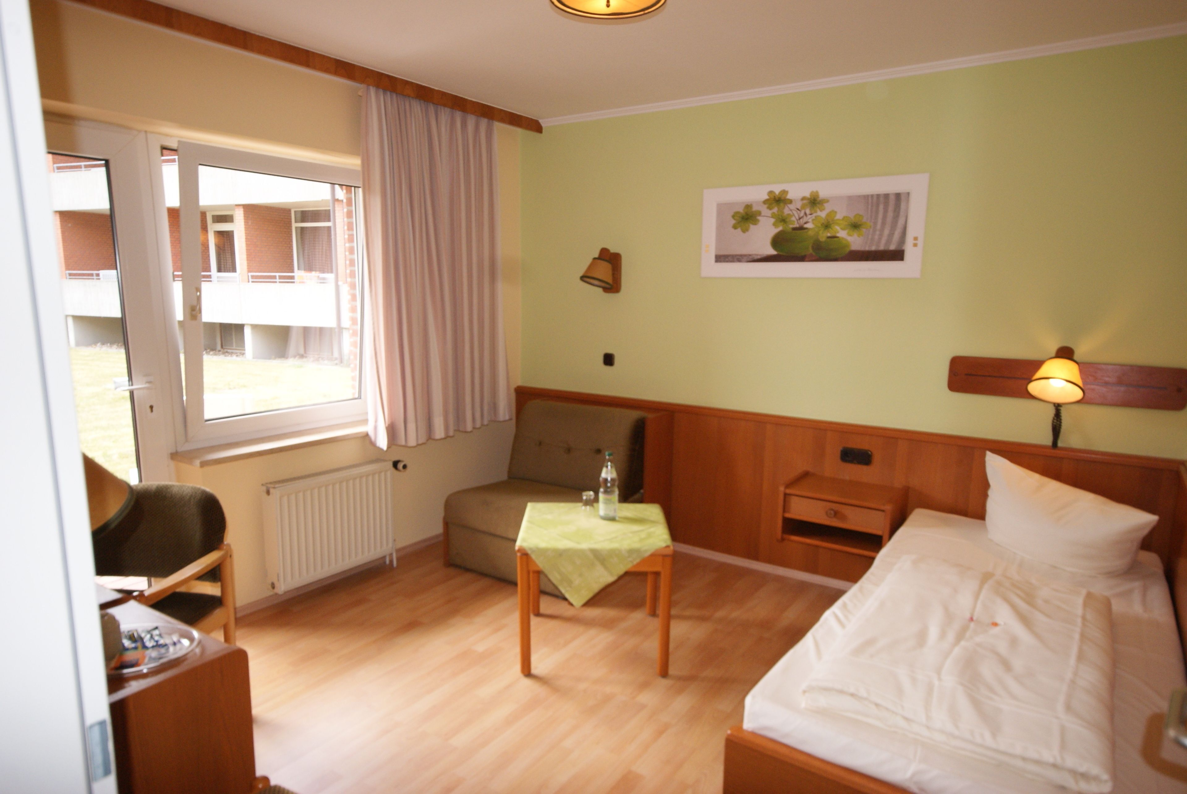 Une chambre d’hôtel avec un lit, une petite table, une chaise, une fenêtre et une vue sur l’extérieur.