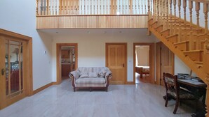 Un vaste espace de vie comprenant un escalier en bois, un canapé et une table à manger.