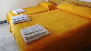Une chambre d’hôtel avec deux lits, chacun recouvert d’une couvre-lit jaune et agrémenté d’oreillers blancs.