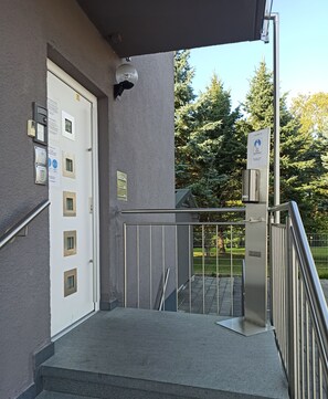 A building entrance with a white door, a metal staircase, and a security gate. - Gästehaus Stock (Friedrichshafen)
