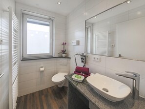 A modern bathroom with a toilet, sink, and a window. - Gästehaus Stock (Friedrichshafen)