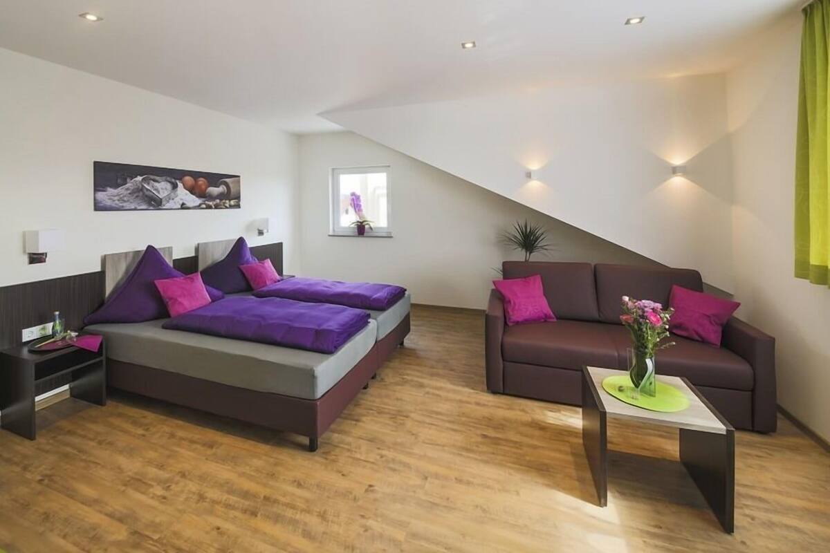 A modern bedroom with a large bed, a sofa, and a small table.